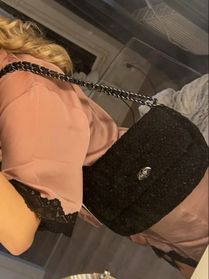 Svart glittrig axelväska med kedja - Svart glittrig axelväska med kedja Från Beck söndergard, aldrig använd och säljs inte längre. Finns fler bilder💗