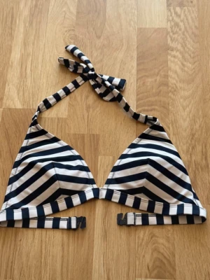 Randig bikiniöverdel med knyt - Snygg bikiniöverdel med marinblå och vita ränder. Triangelformade kupor och knyt i nacken för justerbar passform. Perfekt för strandhäng eller pooldagar.