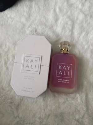 Kayali Vanilla Candy Rock Sugar 42 EdP - Kayali Vanilla Candy Rock Sugar 42 är en parfym i en lyxig, rosa- och guldtonad glasflaska med elegant kristallkork. Doften har noter av sockrad päron, viol, bubbelgum, vit kola, sockersöt rock candy och vaniljkräm. Flaskan rymmer 100 ml och kommer i en stilren, ljus förpackning.