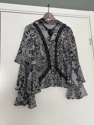 Mönstrad volangblus med vida ärmar - Säljer en unik blus med svartvitt mönster. Blusen har volangiga, vida ärmar. Från Asos design 