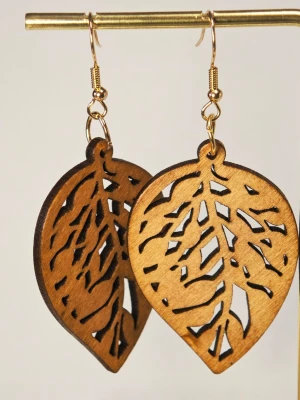 Ultralätta Bruna lövformade träörhängen - Säljer ett par unika örhängen i form av löv, tillverkade i brunt trä med utskurna detaljer som ger en cool och naturlig look. Krokarna är i guldfärgad metall. Perfekta för dig som gillar boho-stil och vill sticka ut lite extra 