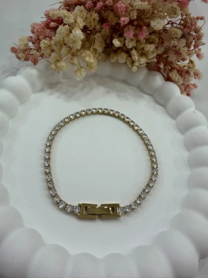 Tennisarmband - Detta exklusiva tennisarmband i rostfritt stål, pläterat med 18K guld, är skapat för dig som uppskattar enkel elegans. Armbandet är dekorerat med gnistrande zirkonstenar som ger ett lyxigt uttryck. Det är dessutom vattentåligt och behåller sin lyster även vid daglig användning. 📏 Längd: 17 cm – sitter bekvämt och stilrent på handleden. Perfekt som en diskret detalj till vardagen eller som ett elegant smycke vid speciella tillfällen 💛 🛍️