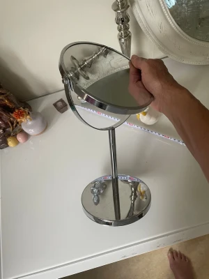 Rund sminkspegel i kromad metall - Snygg rund sminkspegel med kromad metallram och stabil fot. Spegeln är dubbelsidig och kan vinklas för bästa vinkel när du sminkar dig eller fixar håret. Perfekt storlek för sminkbordet och ger en modern touch till rummet.