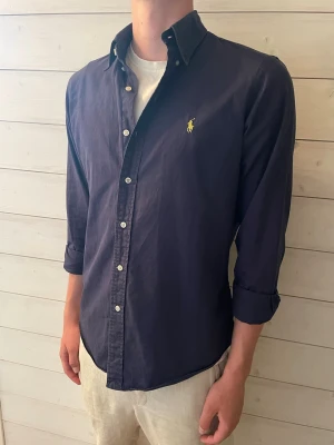 Ralph Lauren skjorta  - En mörk blå snygg Ralph Lauren skjorta i väldigt fint skick/nytt skick!                                          Storlek M.                                                                        Skriv gärna vid några frågor!
