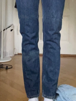 Blå raka jeans från Weekday - Säljer ett par klassiska blå jeans från Weekday med rak passform och hög midja. Jeansen har fem fickor, tydliga sömmar och är gjorda i kraftig denim. Perfekta till en avslappnad stil och funkar året runt.