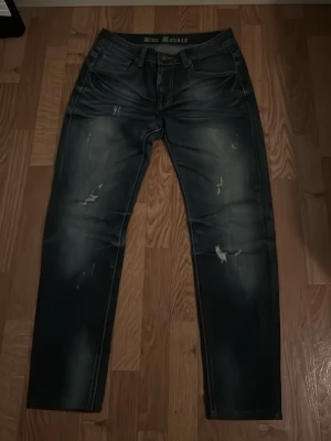Svarta slitna jeans från Blue Monkey - Säljer ett par svarta jeans från Blue Monkey med slitningar och tvättade detaljer. Jeansen har fem fickor, normal midja och raka ben. Snygg streetstil med coola slitningar och en modern look. Perfekta för dig som gillar en avslappnad och trendig vibe pris går att diskuteras vid snabbafär 
