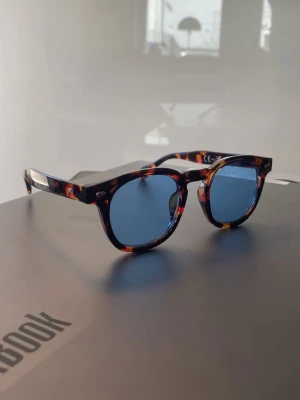 Blåtonade solglasögon i sköldpaddsmönster - Snygga solglasögon med blåtonade runda glas och klassisk sköldpaddsmönstrad båge i bruna och orangea nyanser. Tidlös modell som ger en cool vibe till din outfit. Perfekta för soliga dagar och trendiga looks.