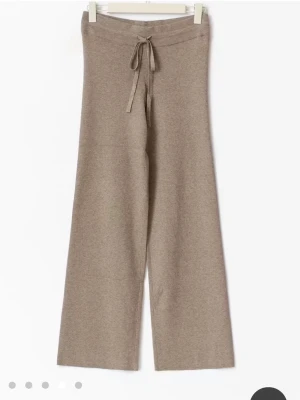 Beiga loungebyxor - Mysiga loungebyxor i beige ribbat material med breda ben och snörning. Perfekta för chill dagar hemma eller när du vill vara bekväm men ändå se snygg ut. Använda 2ggr så i bra skick 