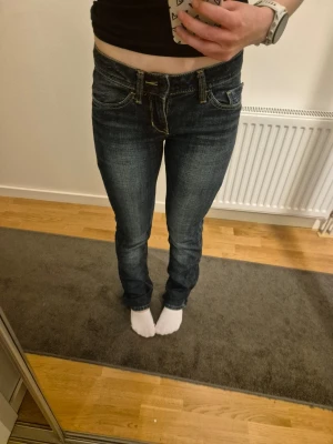Mörkblå bootcut jeans - Esprit casual denim - Säljer ett par mörkblå bootcut jeans med snygga kontrastsömmar och klassiska fem fickor. Jeansen har låg midja och lätt slitningar framtill för en cool look. Perfekta till sneakers eller boots och passar dig som gillar en avslappnad men trendig stil. De är i mycket bra skick. Från esprit casual denim