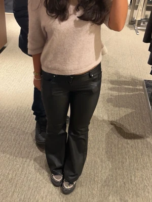 Svarta bootcut skinnbyxor - Snygga svarta byxor i skinnimitation med bootcut passform. de är lågmidjadd och säljer endast då de är för korta för mig som är 165