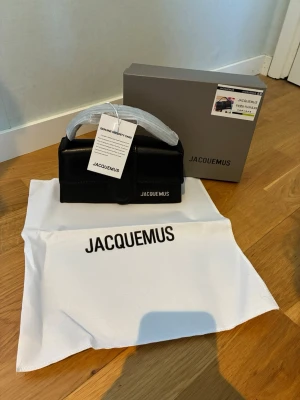 Jacquemus väska  - Säljer en svart Jacquemus väska i slätt läder. Väskan har ett stilrent, rektangulärt format med ett topphandtag och silverfärgad Jacquemus-logga på framsidan. Kommer med originalkartong, dustbag och äkthetskort.
