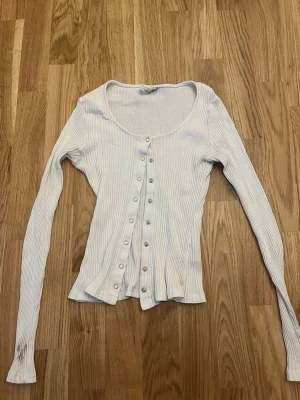 Vit ribbad kofta med knappar - Snygg vit ribbad kofta med långa ärmar och silverfärgade knappar framtill. Smutsig på ena armen