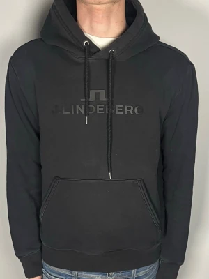 J.Lindeberg Hoodie - Säljer en snygg J.Lindeberg hoodie, snygg svart färg med clean tryck i mitten! Passar bäst på någon runt 180cm skulle jag säga, för kort för mig på 186cm. Tveka inte på att skriva om du har några frågor eller funderingar💯