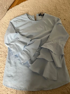 Ljusblå blus med volangärmar - Snygg ljusblå blus med rund halsringning och armar med dubbla volanger.💕