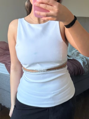 Vit ärmlös topp med strassdetalj - Säljer denna supersnygga vita toppen med silverstrass detaljer och cut out, endast använd en gång 🥰 