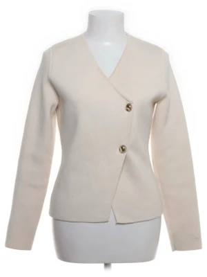 Krämvit kofta med guldknappar - Stilren krämvit kofta/ kavaj aktig med två dekorativa guldknappar framtill. Koftan har V-ringning, lång ärm och rak/ kroppsformad passform. Perfekt för dig som gillar minimalistisk och elegant stil. 