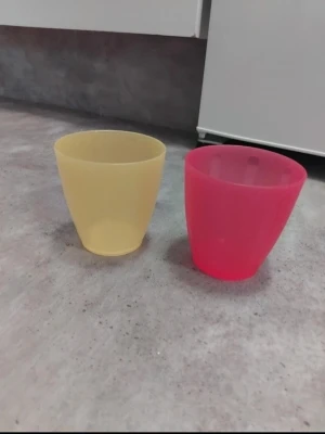 Två plastmuggar i gult och rosa - Säljer två enkla plastmuggar, en i ljusgul och en i rosa. Muggarna har rundad form och är perfekta för vardagsbruk, picknick eller till barn. Tillverkade i tålig plast och lätta att stapla.