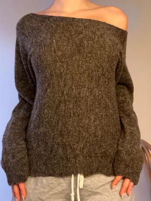 Mörkgrå off shoulder stickad tröja - Mysig mörkgrå stickad tröja med off shoulder-design och avslappnad passform. Tröjan har långa ärmar och ribbade muddar vid ärmslut och nederkant. Perfekt för lager på lager och en chill look. Använd max 3 gånger och säljer en likadan i ljusgrå!🩶🤎