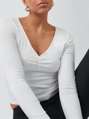 Vit topp med v-neck - Säljer en stilren vit croppad topp med lång ärm och snygg v-ringning. Toppen har en lätt rynkning vid bysten som ger en extra detalj. Perfekt att matcha med både jeans och kjol. Materialet känns mjukt och stretchigt.