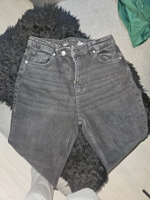 Svarta jeans - Säljer ett par svarta jeans från Ullared med hög midja och raka ben. Jeansen har klassisk femficksdesign och är gjorda i mjukt denimtyg. Perfekta för en avslappnad och trendig look.