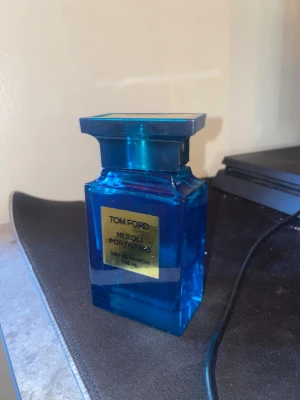 Tom Ford Neroli Portofino parfym 100ml - Tom Ford Neroli Portofino Eau de Parfum i en lyxig, blå glasflaska med guldlabel. Flaskan rymmer 100 ml och har en elegant, fyrkantig form. En ikonisk doft som utstrålar exklusivitet och stil.