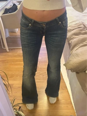 Lågmidjade mörkblå jeans  - Säljer ett par mörkblå jeans med snygg bootcut och låg midja. Jeansen har klassisk femficksdesign, diskreta slitningar och sitter tajt upptill med utsvängda ben. Lite otydliga bilder men kan skicka fler privat om det önskas, de är i storlek M men passar en S också då de är lite små i storleken! De är även i längd Full alltså lite längre, men uppsydda så de passar mig som är 164😊 Har bara använt 4 gånger!