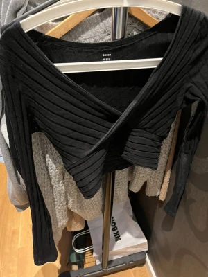 Svart croppad omlottopp från SHEIN - Snygg svart croppad och ribbad omlottopp från SHEIN. Toppen har lång ärm och djup v-ringning. 