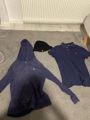 säljer Ralph lauren bundle - Säljer ett snyggt paket från Ralph Lauren som innehåller:  * Piké * Mössa * Zipper  Alla plagg är i bra skick förutom zip-tröjan som har 2 mindre fläckar (se bild). Annars är allt helt och fräscht. Kan visa fläckar privat.  Pris: 400 kr (kan diskuteras vid snabb affär)