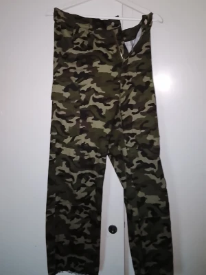 Cargobyxor/jeans i camomönster 36 point 5 - Säljer ett par cargobyxor/jeans i camouflagemönster från 36 point 5. Byxorna har raka ben och flera praktiska fickor. Färgerna går i grönt, brunt och svart. Perfekta för dig som gillar streetwear eller vill ha en cool militärstil. 