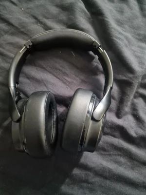 Svarta over-ear hörlurar från MPOW - Snygga svarta over-ear hörlurar från MPOW med vadderad bygel och mjuka öronkuddar i konstläder. Hörlurarna har en stilren design och är perfekta för musik, gaming eller videos. Slitstarka material och bekväm passform för längre lyssningssessioner.