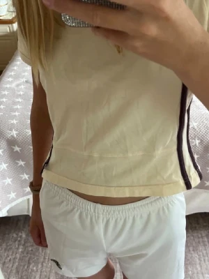 Vita Adidas shorts  - Snygga vita Adidas shorts med climalite-teknologi som håller dig sval. De har elastisk midja för skön passform och är tillverkade i lätt polyester. Perfekta för sport eller chill, med diskret Adidas-logga på benet. Det står storlek 152, men passar mig som har stl xs-s. De har snören som man kan dra åt i midjan (se bild 4). De är färgat blått lite av tvättmedel i innertyget (bild 6) men inget som syns. Pris går att diskutera! Hör av er om frågor och kontakta mig innan köp!❤️(Säljer även på Vinted)