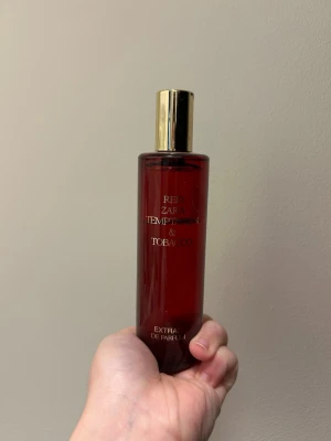 Zara Red Temptation & Tobacco parfym - En stilren parfym från Zara i en mörkröd, cylinderformad glasflaska med guldfärgat lock. Doften heter Red Temptation & Tobacco och är en Extrait de Parfum, vilket ger en intensiv och långvarig doftupplevelse. Har använt parfymen och är kvar så mycket fram till texten ”tempatation”