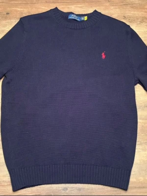 Mörkblå stickad tröja Polo Ralph Lauren - Klassisk mörkblå stickad tröja från Polo Ralph Lauren. Tröjan har den ikoniska röda logotypen broderad på bröstet. Nytt skick bara provat en gång men för stor storlek. Hör av er om frågor 👍
