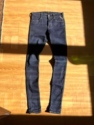 Mörkblå skinny jeans från Replay - Säljer ett par mörkblå skinny jeans från Replay med klassisk femficksdesign och snygga kontrastsömmar. Jeansen har låg midja och smal passform hela vägen ner. Perfekta för dig som gillar en tight och modern look.