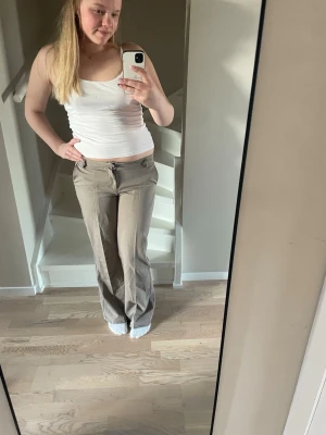 Beige kostymbyxor med utsvängda ben - Fina  beige kostymbyxor!! Har sytt upp byxorna då de var för långa för mig, men de går lätt att sprätta upp om man skulle vilja. Originalpris: 599kr 
