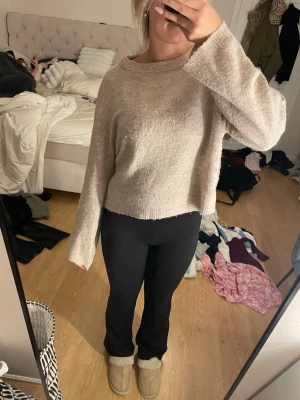 Beige stickad tröja från 157 - Mysig beige stickad tröja från 157 med avslappnad passform och långa ärmar. Tröjan har ribbade muddar vid halsen och är tillverkad i ett mjukt material som känns skönt mot huden. Perfekt för lager på lager och enkel att matcha till olika outfits.
