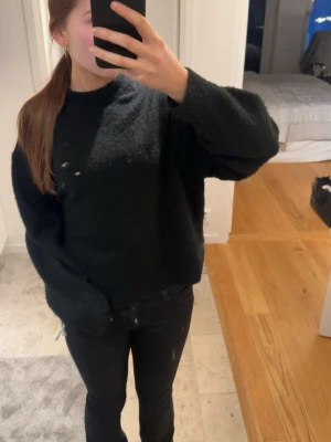 Svart stickad tröja - Mysig svart stickad tröja med lång ärm. Perfekt att slänga på sig till jeans, kjol eller short, varför inte nu till sommaren? Tröjan är använd och några få knottror finns på den. Kommer tyvärr ej till användning längre. Hör av dig vid frågor!
