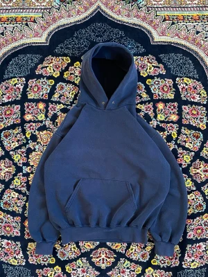 Mörkblå hoodie med huva - Säljer en stilren mörkblå hoodie med stor huva och magficka. Hoodien har ribbade muddar vid ärmslut och nederkant, samt en klassisk avslappnad passform. Perfekt för en chill och avslappnad look.