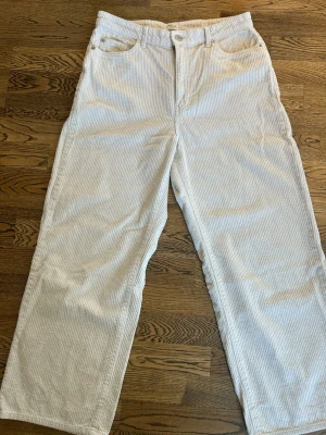 Vita manchesterbyxor från Lindex - Säljer ett par ankellånga beige/vita manchesterbyxor från Lindex i storlek 40. Byxorna har raka och ganska vida ben. Klassisk femficksmodell och stängs med knapp och dragkedja. Materialet är mjuk manchester.