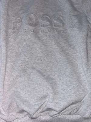 Grå sweatshirt från Hugo Boss - Snygg grå sweatshirt från Hugo Boss med broderad logga framtill. Perfekt för en avslappnad och stilren look.