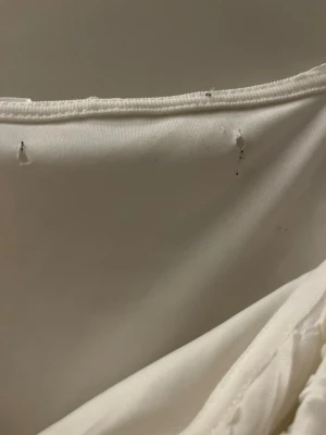 Vit volangig linnetopp - En mycket speciell och fin vit topp med massor av volanger och liv vid ärmarna. Den har en rolig struktur i tyget och passar perfekt när man vill vara lite extra fin. Finns små hål där prislappen brukade vara eftersom min hund bitit av den.