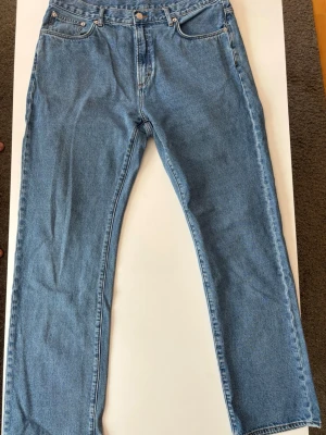 Blå raka jeans från Brothers  - Ett par ljusblå jeans med rak passform och fem fickor. Jeansen har normal midja, dragkedja och knapp framtill samt klassiska sömmar. Tillverkade i denim, perfekt för en avslappnad stil.