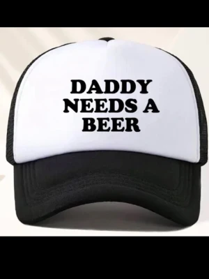 Svartvit keps  - Säljer en svart och vit truckerkeps med texten 'DADDY NEEDS A BEER' tryckt framtill. Kepsen har klassisk böjd skärm och mesh på sidorna och bak, vilket ger bra ventilation. Justerbar storlek med snapback-spänne. Perfekt för dig som gillar humoristiska accessoarer.