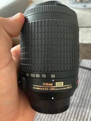 Nikon AF-S DX 55-200mm objektiv - Säljer ett svart Nikon AF-S DX 55-200mm f/4-5.6G ED objektiv. Objektivet har zoomring med tydliga markeringar och är tillverkat i plast och glas. Passar till Nikon DX-kameror och har VR-funktion för bildstabilisering.
