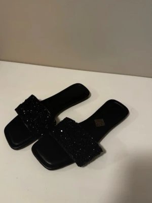 Svarta sandaler med glitter - Stilrena svarta sandaler med fyrkantig tå och bred rem dekorerad med svarta pärlor och glitter. Säljer då dem är förstora🩷