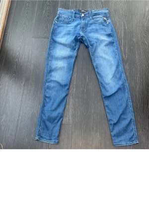 Blåa replay jeans - Snygga blå jeans från Replay med klassisk femficksdesign och raka ben. Jeansen har en ljus tvätt och tydliga sömmar, samt en patch med Replay-logga bak i midjan. Perfekta för en avslappnad och trendig look. W29 L32