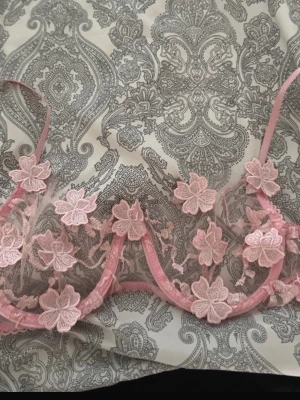 Rosa spets-bh med blommor - Säljer en superfin rosa bh med transparent mesh och broderade blommor i spets. Bh:n har tunna axelband och bygel för extra stöd. Perfekt för dig som gillar romantiska detaljer och en feminin look.