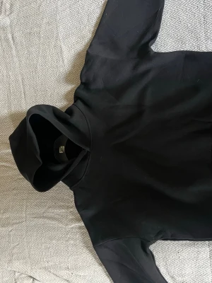 Svart hoodie från Saint Alexander - Säljer en stilren svart hoodie från Saint Alexander. Hoodien har en klassisk huva och är gjord i mjukt material som känns skönt mot huden. Perfekt för dig som gillar en enkel och clean look. Passar till det mesta och är lätt att matcha med andra plagg.