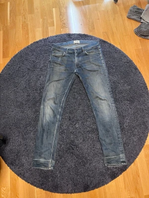 Blå slim fit jeans från Acne Studios - Säljer ett par blå slim fit jeans från Acne Studios med klassisk femficksdesign och dragkedjegylf. Jeansen har en snygg tvättad look och smala ben. Perfekta för dig som gillar stilrena och trendiga jeans.