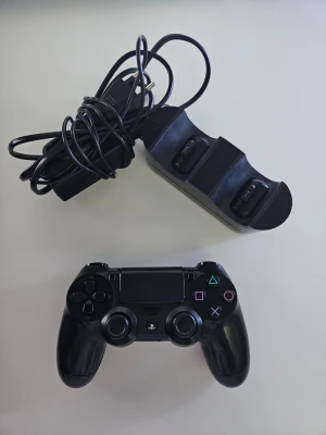 Svart PS4 DualShock 4 handkontroll - Säljer en svart DualShock 4 handkontroll till PlayStation 4 från Sony. Medföljer gör en laddstation för två kontroller samt strömkabel. Handkontrollen har klassisk layout med touchpad, LED-ljus och ikoniska PlayStation-knappar. Perfekt för gamingkvällar! Allt fungerar perfekt, priset kan diskuteras